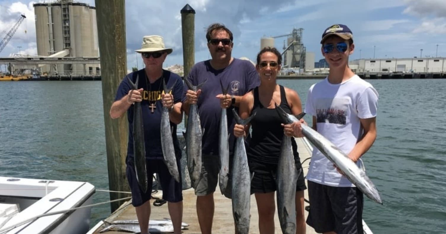 Group of anglers posing with wahoo and kingfish on fishing charter