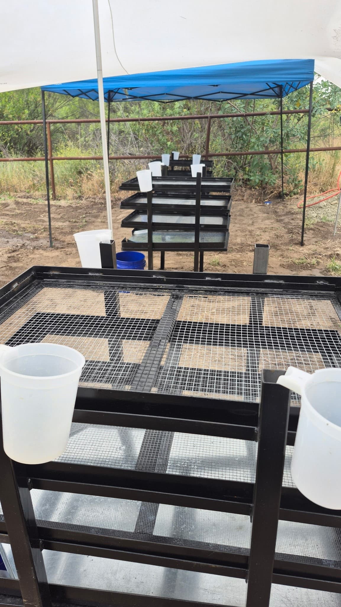 Stacked screening frames under canopy at fossil dig site