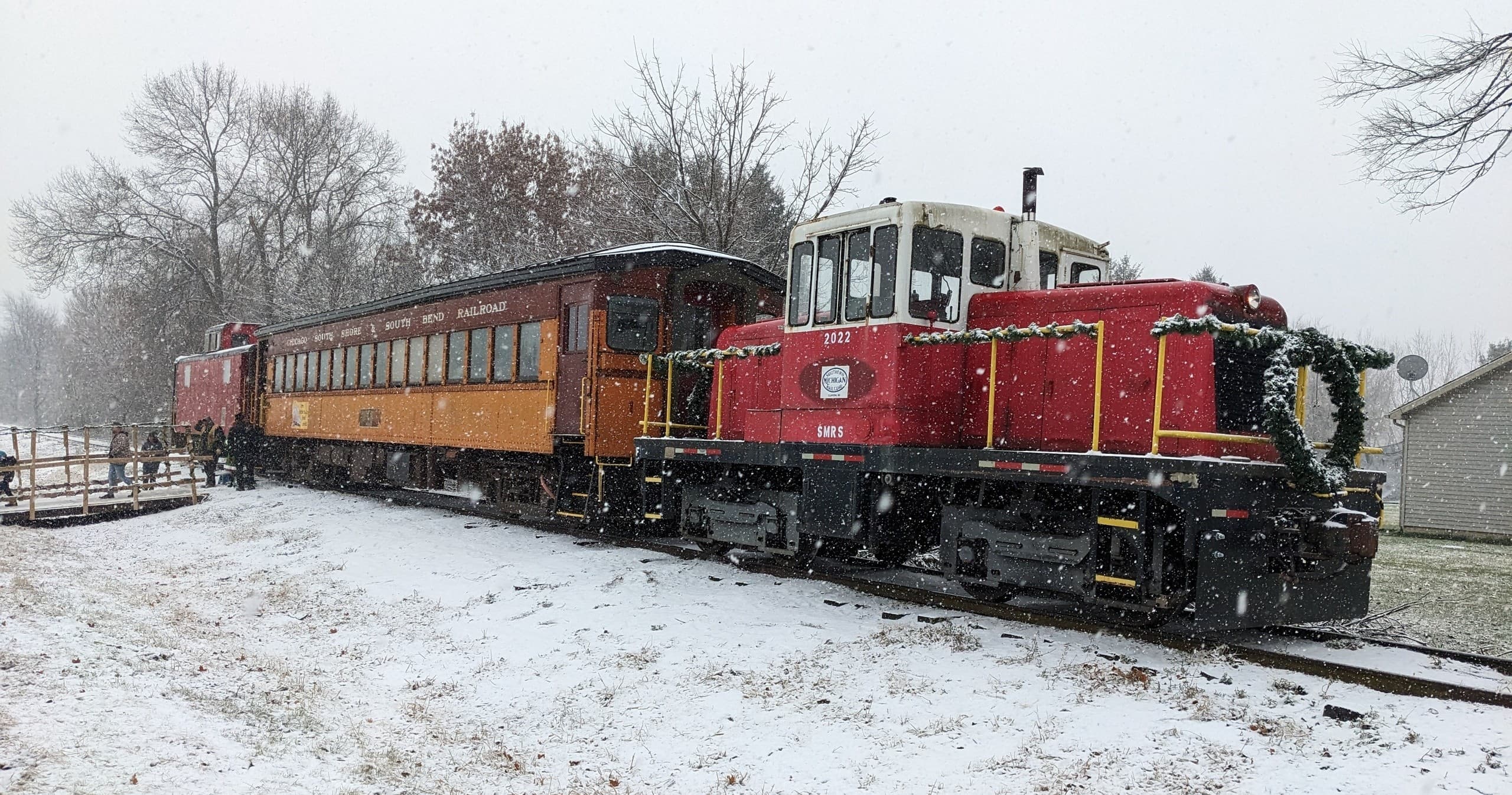 Vintage red locomotive pulling passenger cars through snow