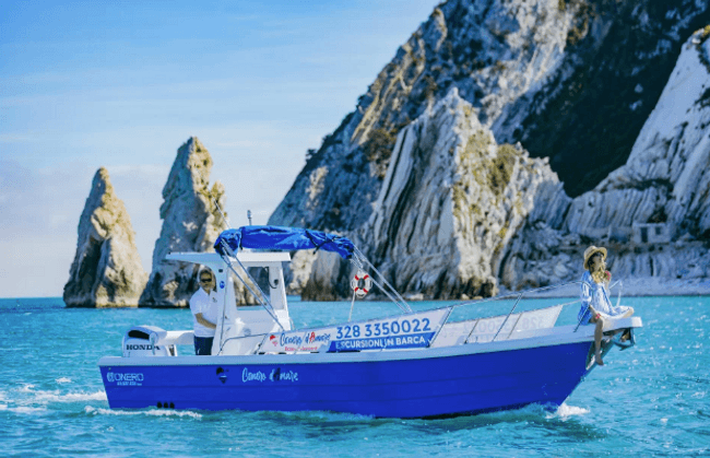 Blue tour boat cruising near coastal limestone cliffs, passengers