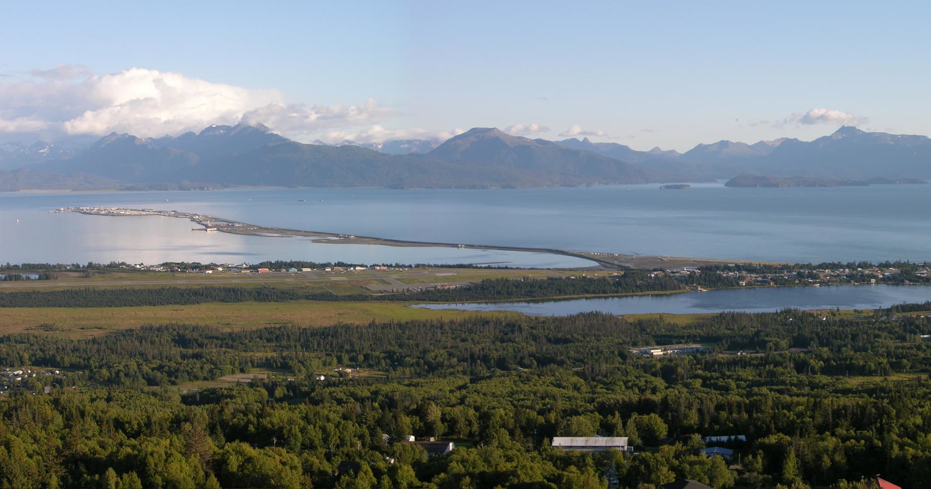 Panoramic coastal vista over Alaskan bay with mountain backdrop