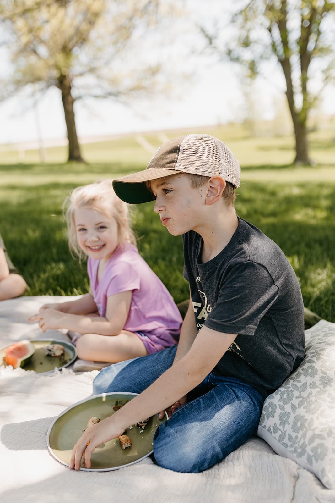 Kids enjoying a picnic on a blanket under trees at the farm