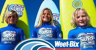 Three surf groms smiling with surfboards in beach surf school promo