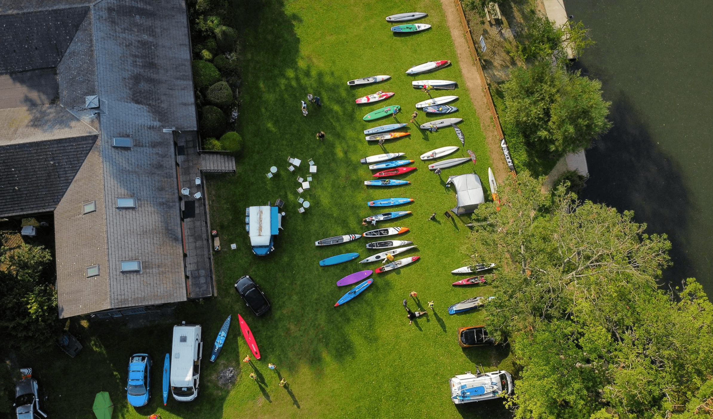 Aerial view of kayaks and paddleboards staged on riverbank