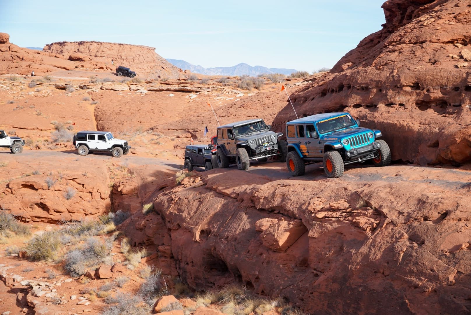 Off-road Jeep convoy traversing red rock desert trail in Moab