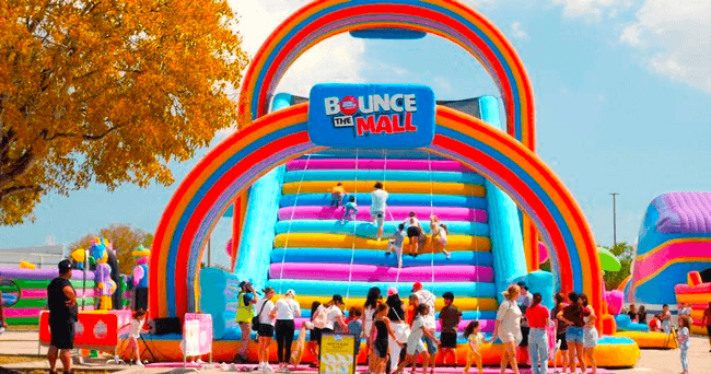 Kids enjoying giant inflatable slide at outdoor bounce park