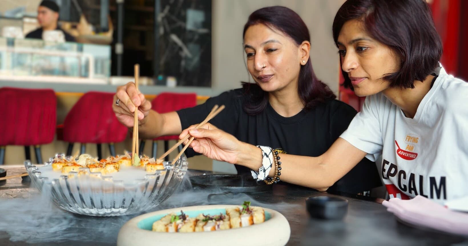 Friends sampling modern fusion dishes at indoor communal dining table