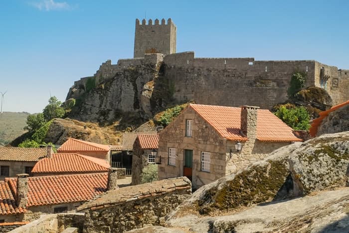 Hilltop medieval castle above red-tiled village, rustic panorama
