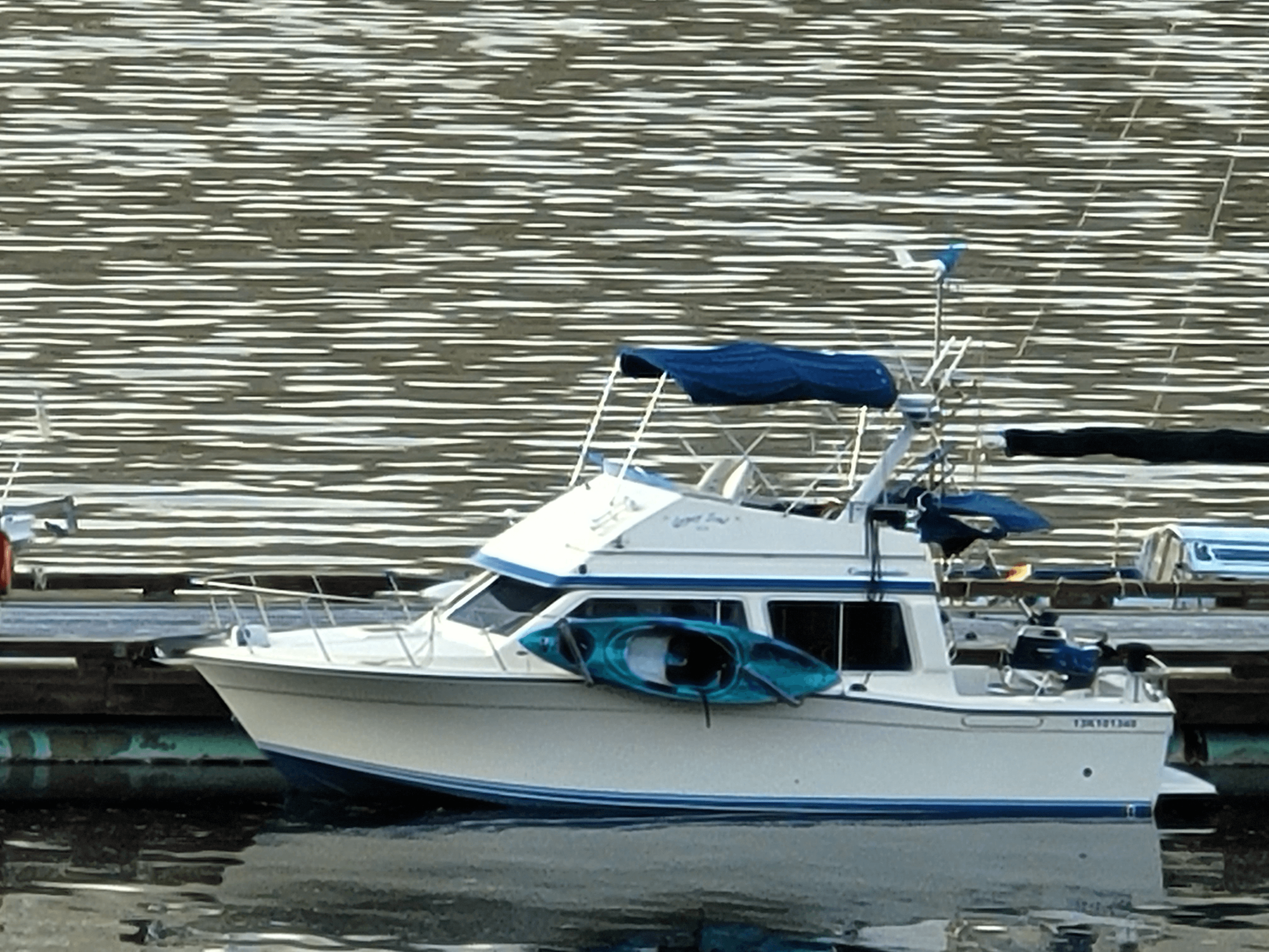 Small cabin cruiser moored at marina with paddles and gear aboard