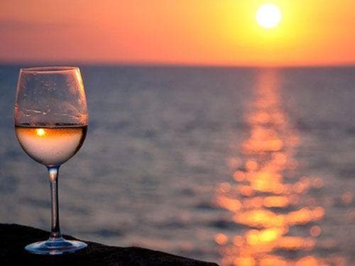 Wine glass on beach at sunset, seaside wine tasting and relaxation