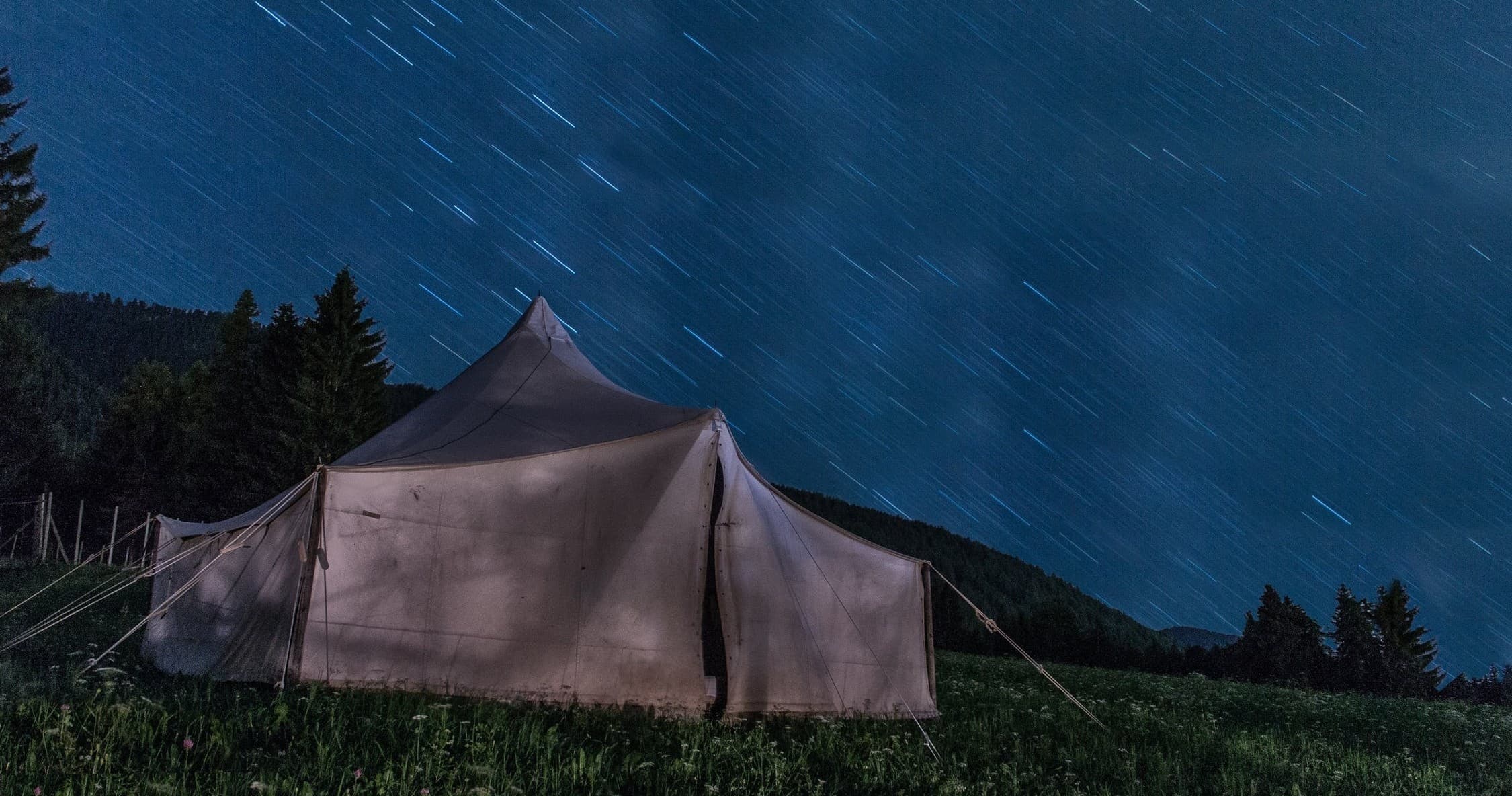 Large canvas tent under starry night sky at backcountry camp