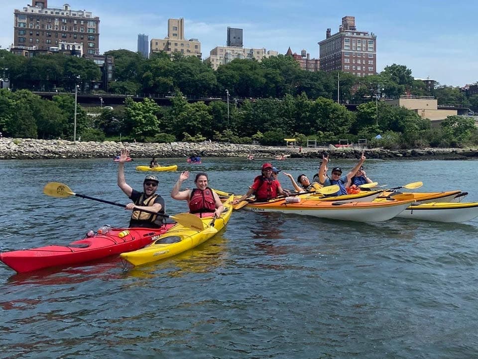 Kayakers paddling near Brooklyn skyline on open water