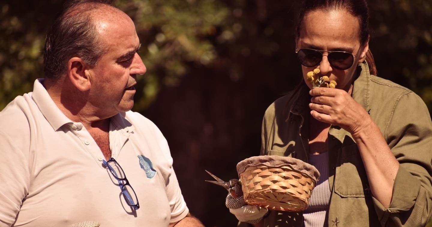 Host and guest sampling aromatic herbs from basket outdoors