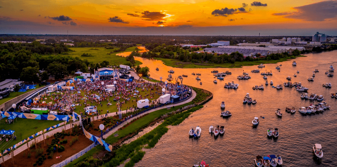 Sunset aerial of waterfront festival with boats and shoreline crowd