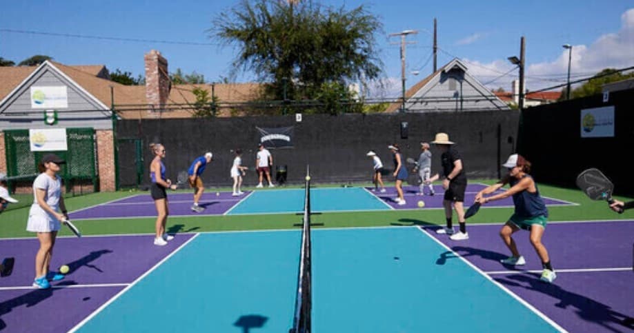 Players playing pickleball on colorful outdoor courts in sunlight