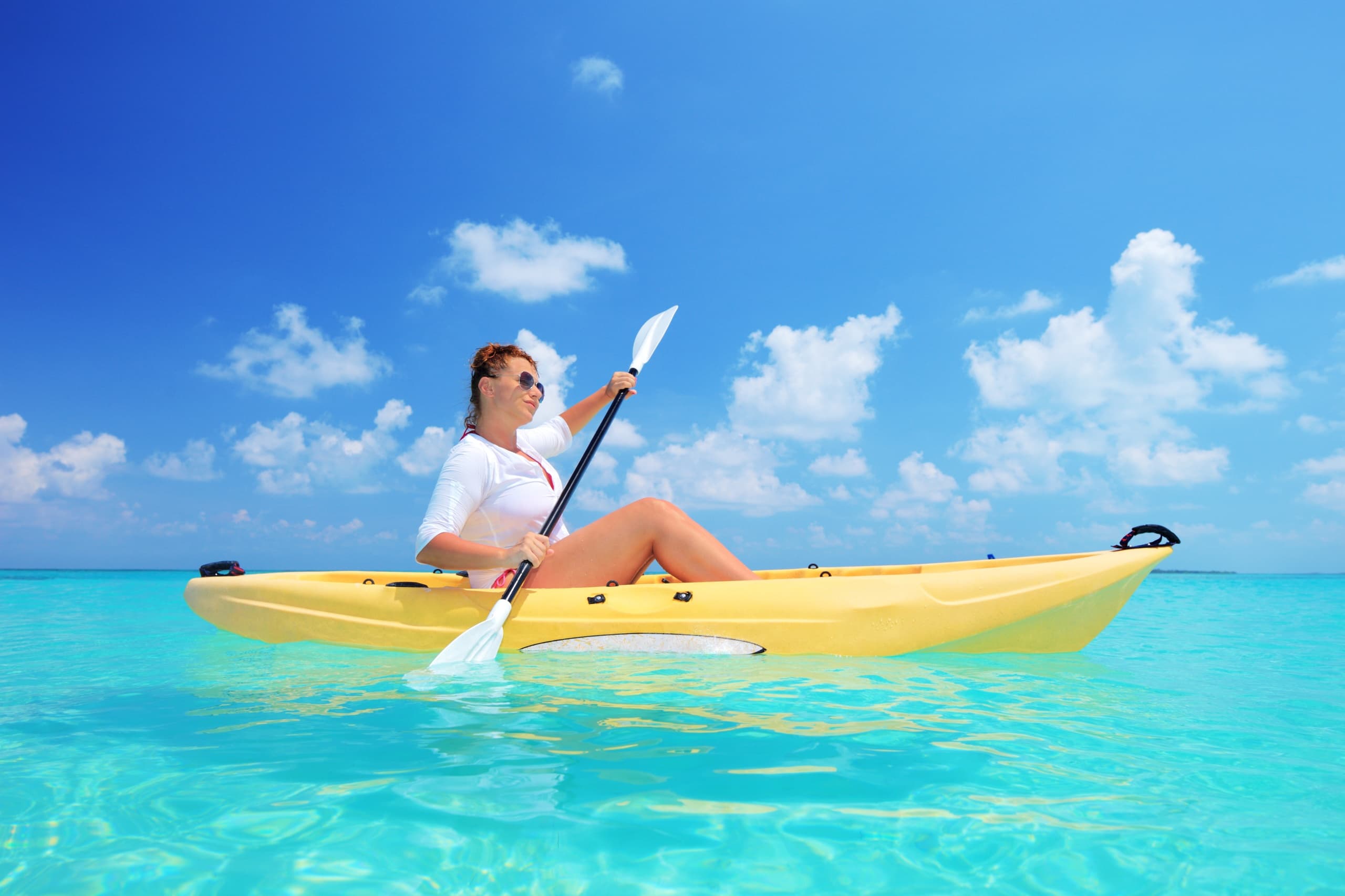 Solo kayaker paddling on clear turquoise tropical ocean waters