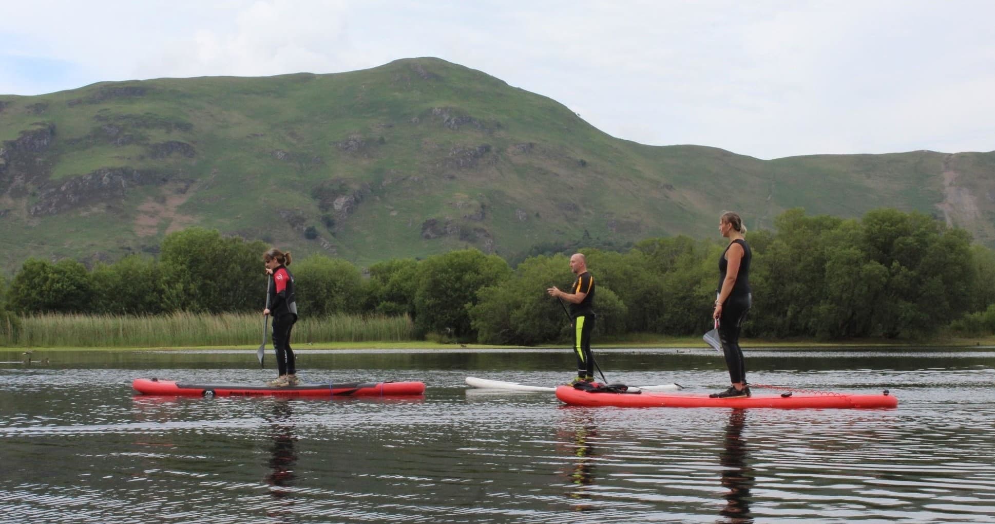 Stand-up paddleboarders on tranquil lake with mountain backdrop