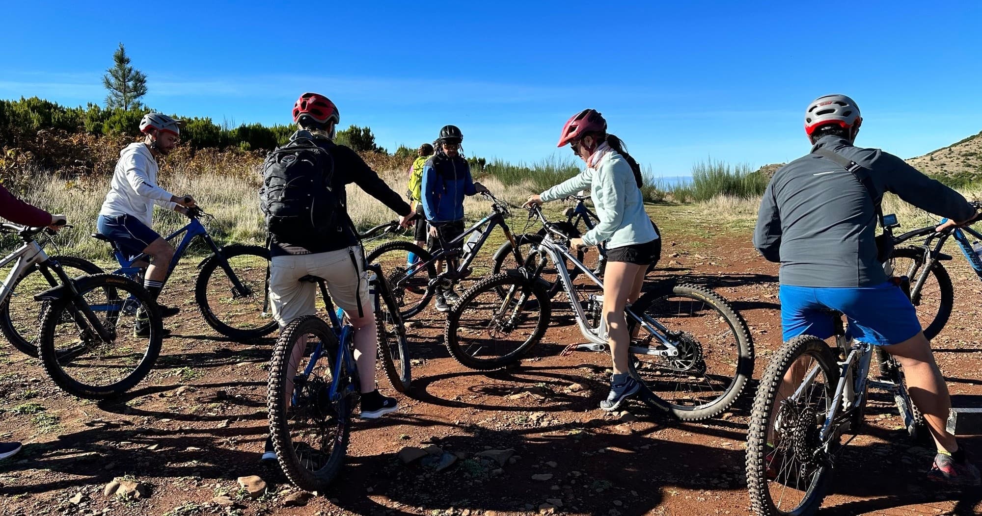 Group mountain biking on volcanic trails in Madeira with coastal views