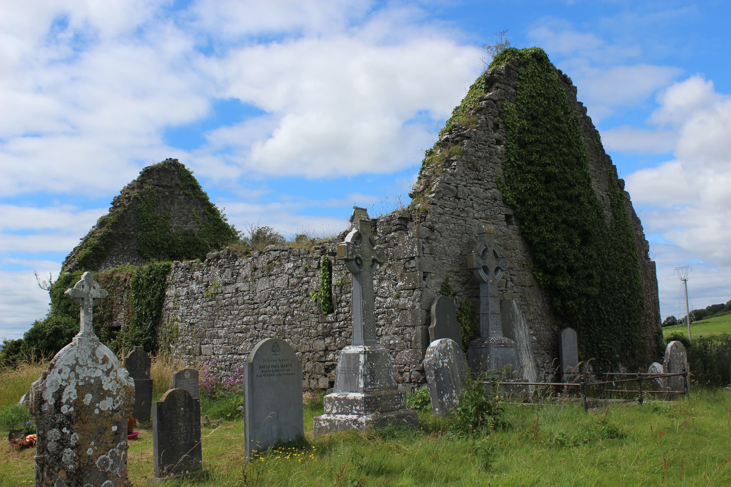 Ivy-covered medieval church ruins and graveyard, rural landscape