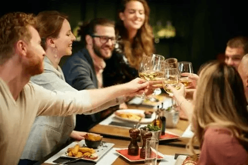 Group dining and toasting at indoor culinary social dinner event