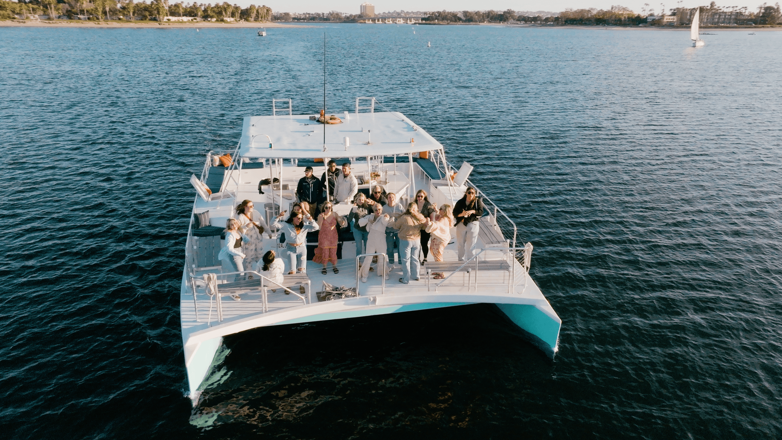 Aerial view of party catamaran approaching coastal shoreline
