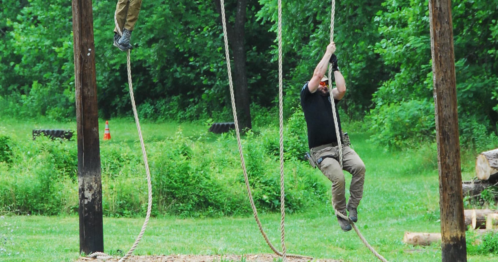 Man climbing rope obstacle on wooded outdoor training course
