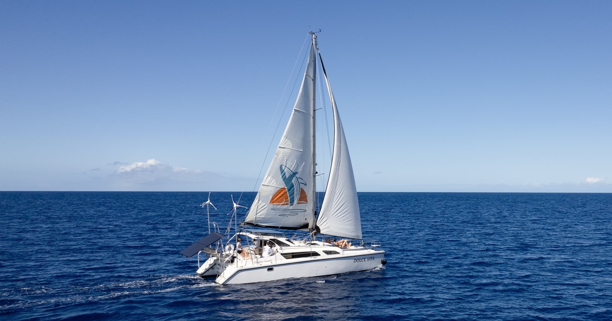 Sailboat cruising on open ocean under clear blue sky