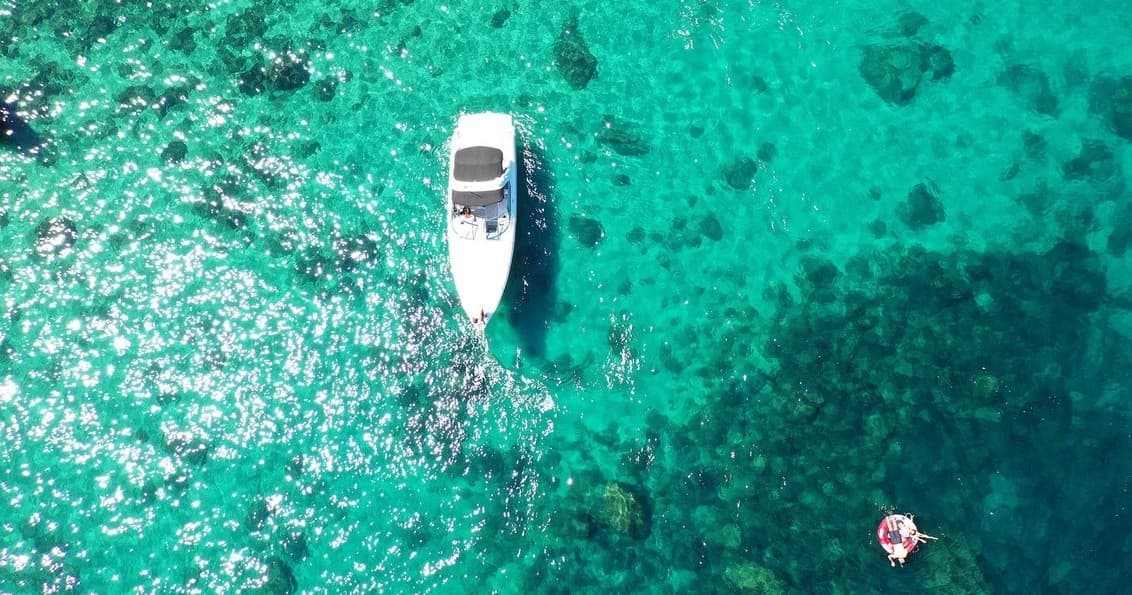 Aerial view of single boat over turquoise water near reef