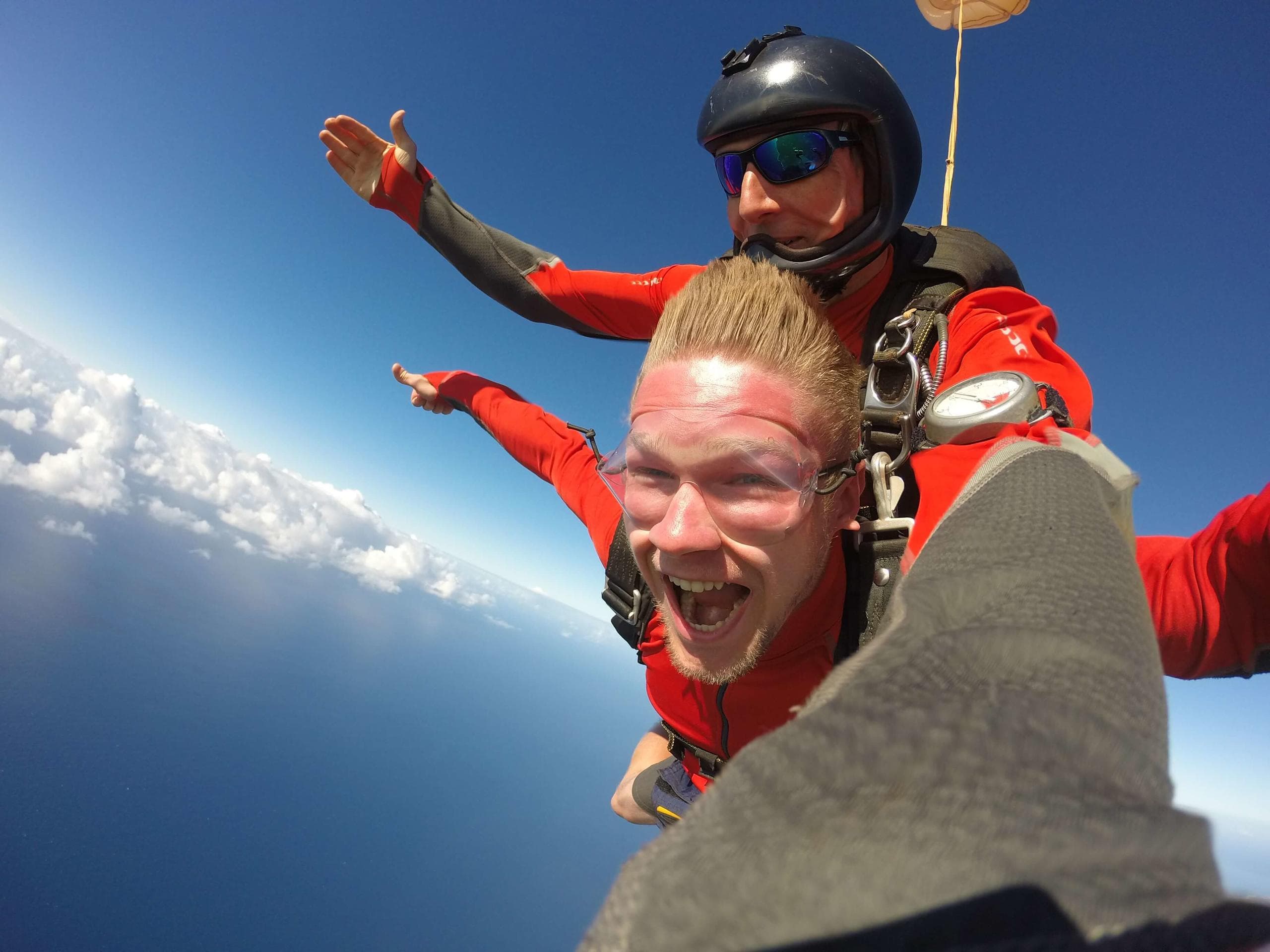 Excited tandem skydiver over Kauai ocean with instructor