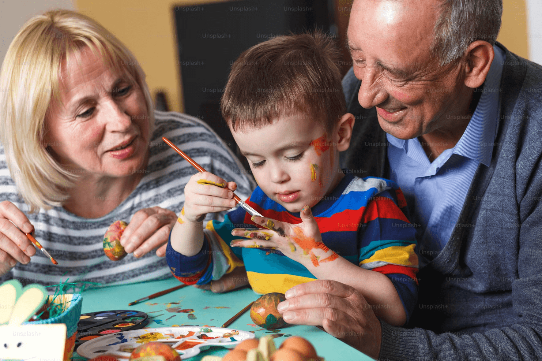 Grandparents painting with child during family art class indoors