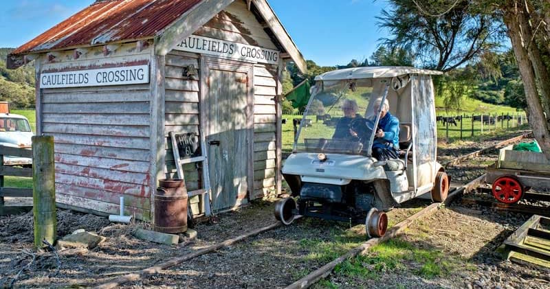 Vintage rail trolley beside rustic crossing shed in rural setting