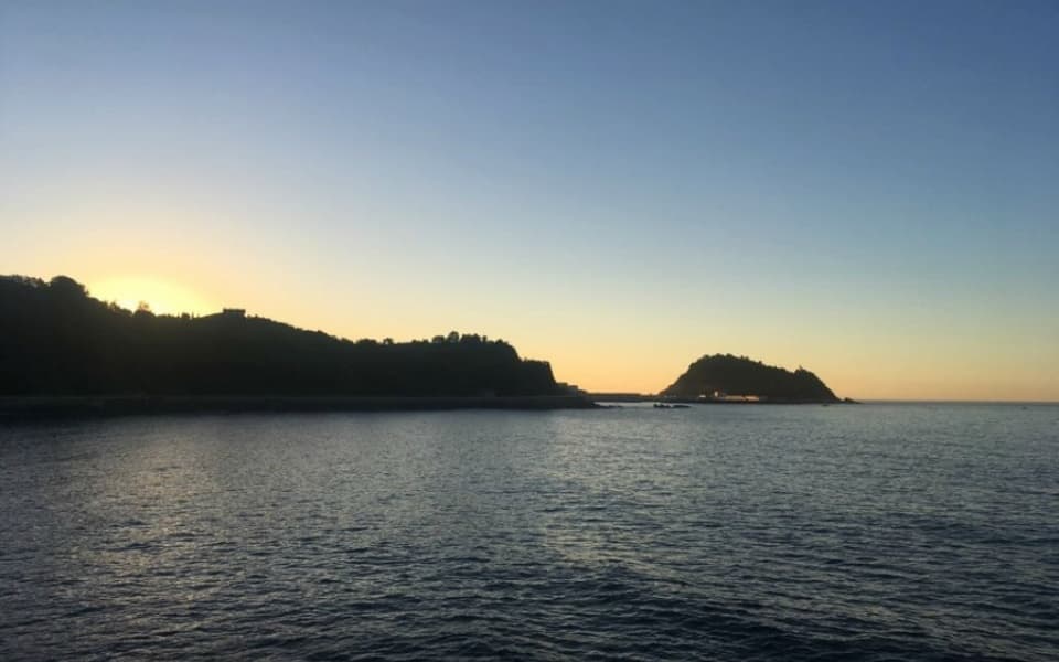 Sunset over calm bay with rocky island on Basque seascape