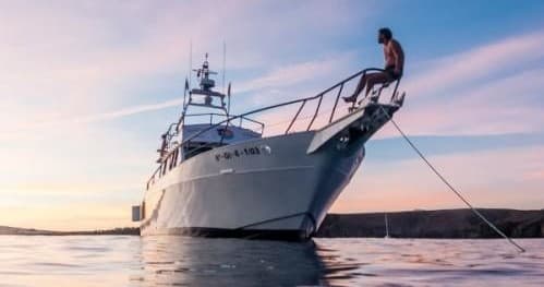 Motor yacht anchored at sunset on calm open ocean