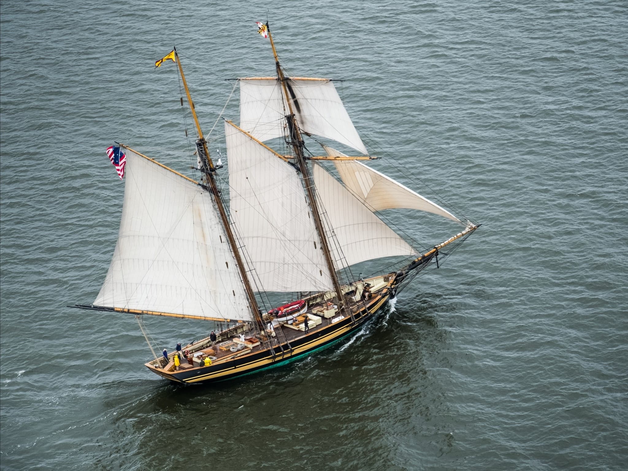 Classic two-masted schooner under sail on choppy coastal waters