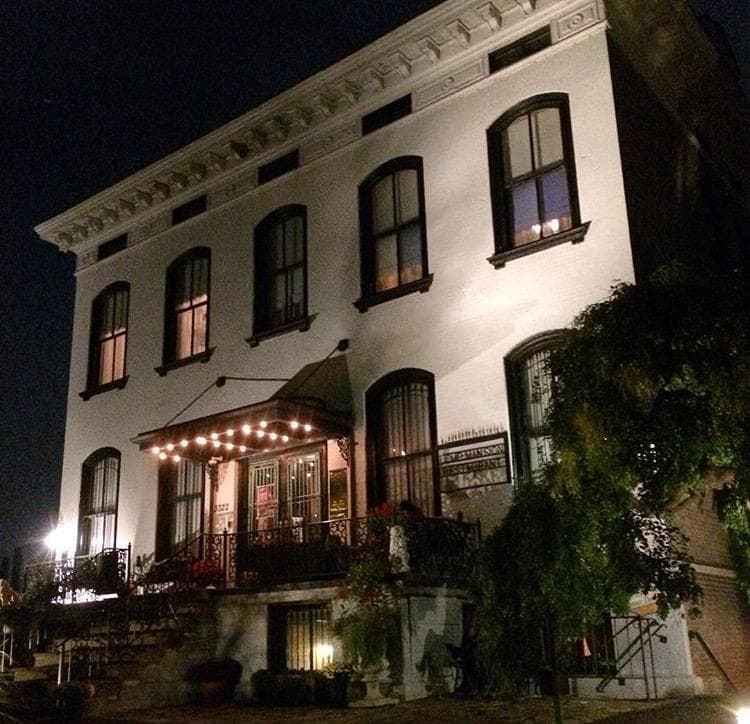 Illuminated Lemp Mansion entrance at night with porch lights