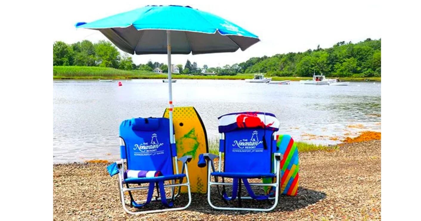 Beach chairs under umbrella on lakeshore at sunny resort beach