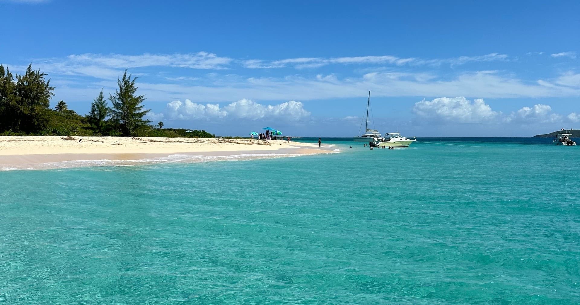 Sailboats near white sand Caribbean beach in turquoise water