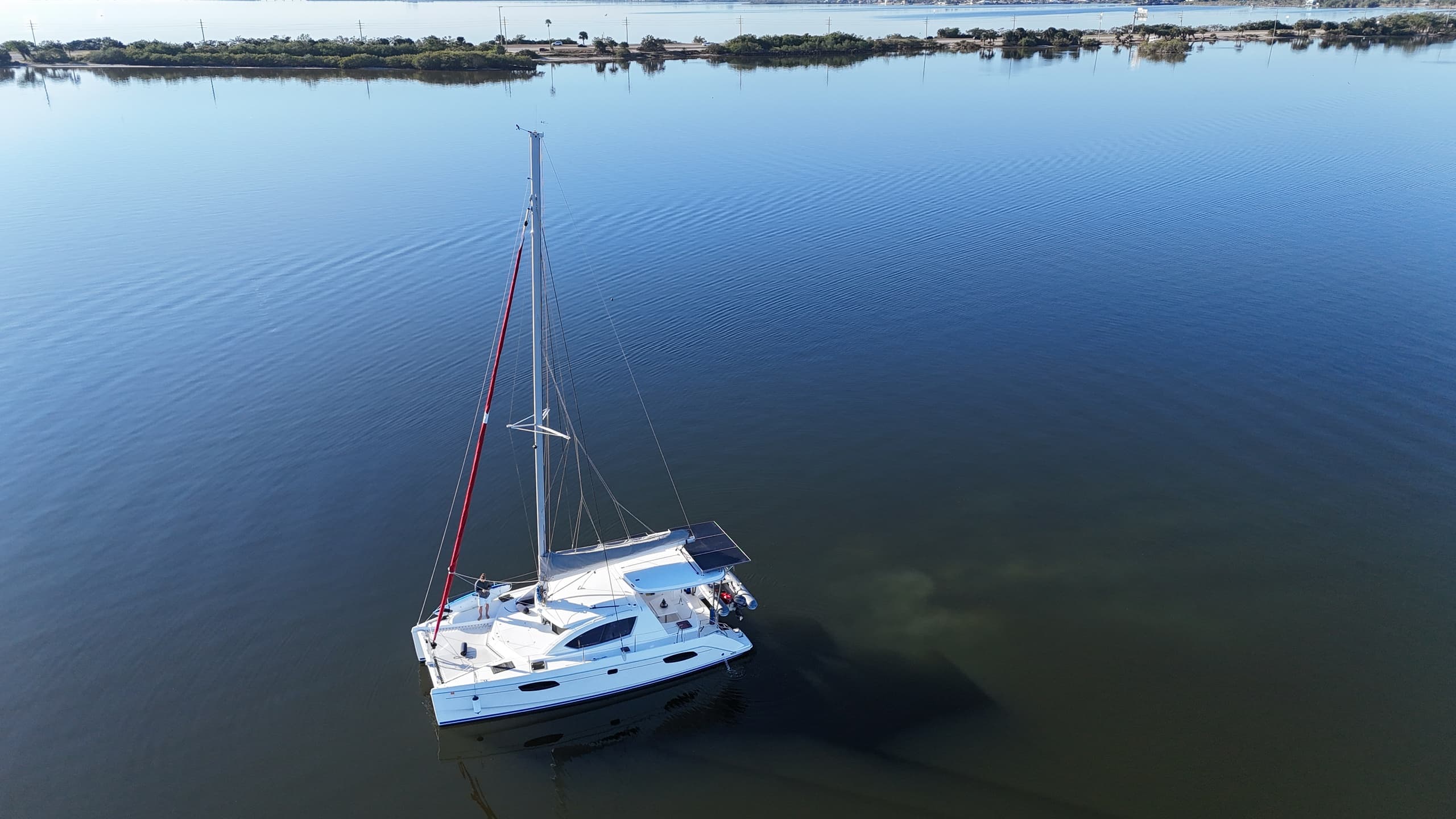 Aerial catamaran on mirror-like coastal estuary at dawn