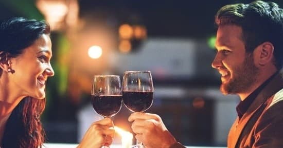 Couple toasting red wine in dim indoor restaurant setting