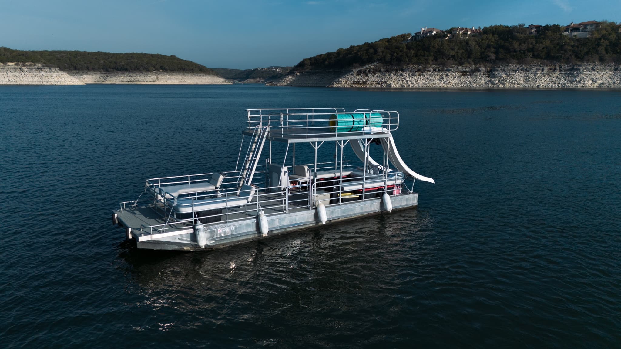 Family pontoon with water slide on scenic lake with shoreline