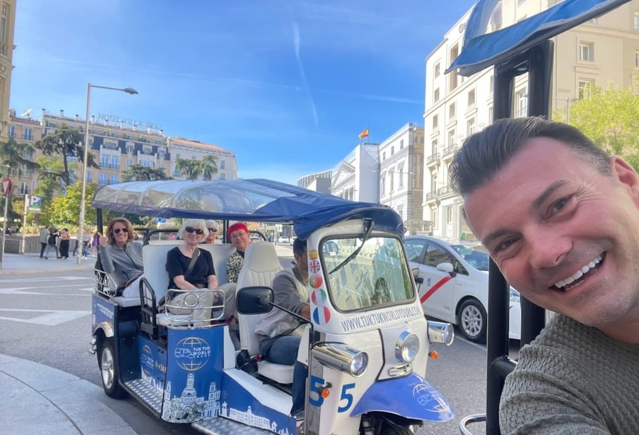 Selfie of guide with tuk-tuk on busy city avenue tour