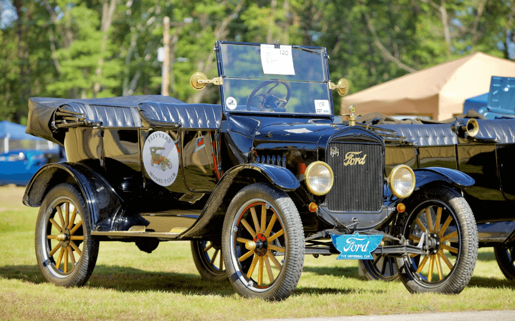 Black vintage Ford touring car on grassy field at outdoor show