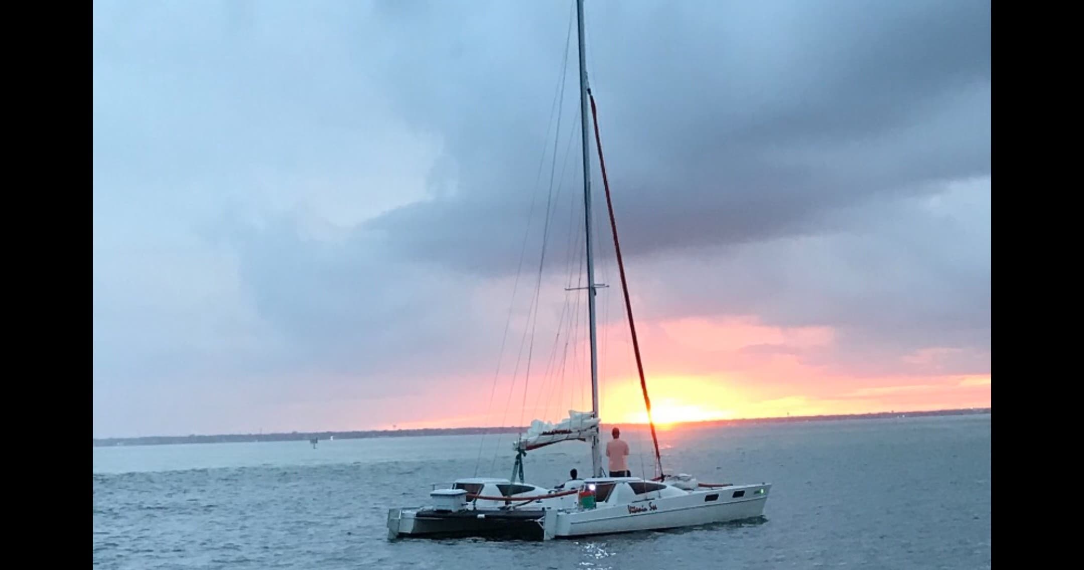 Catamaran anchored at sunset on calm coastal waters, tranquil sail