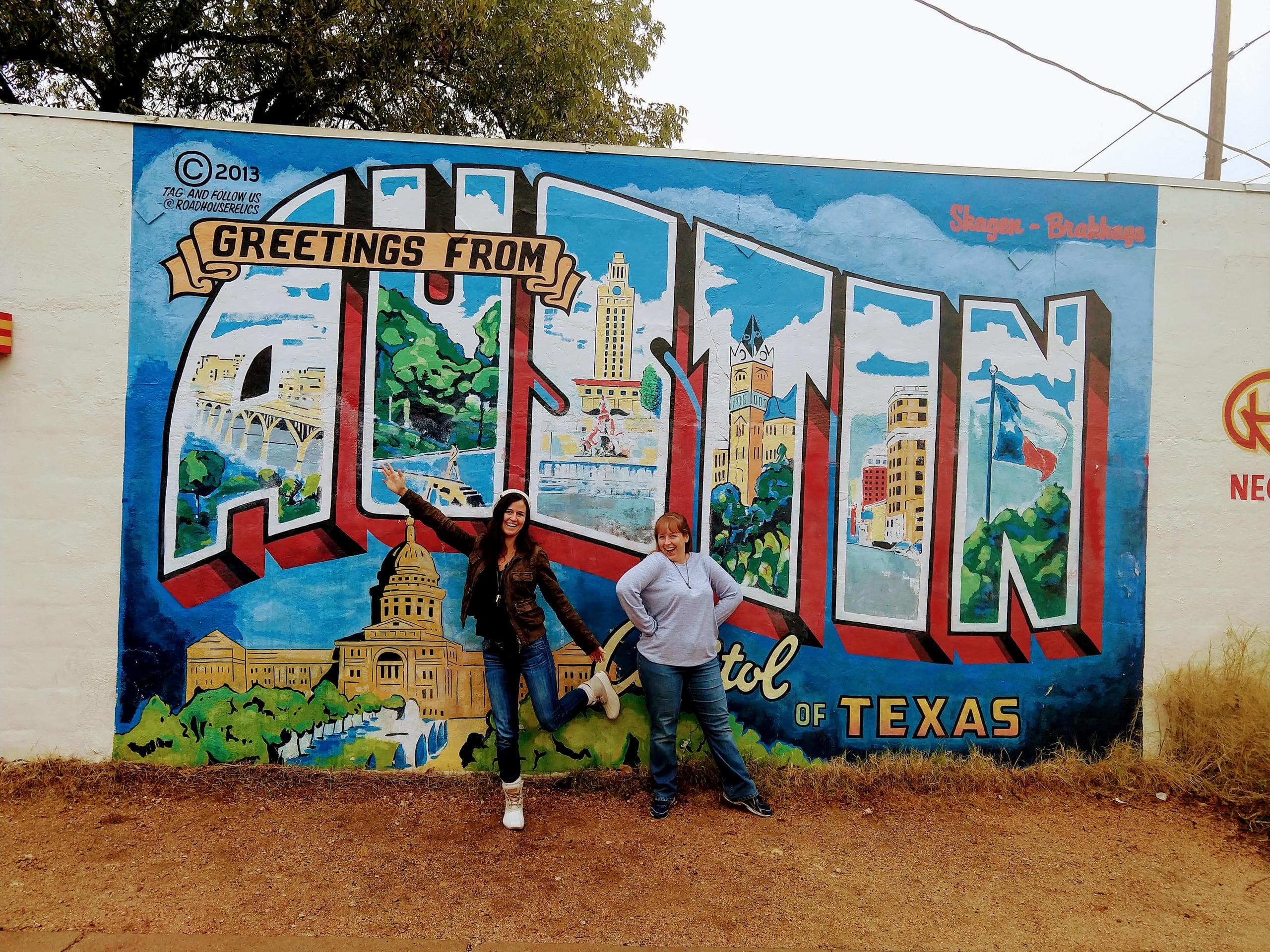 Couple posing by large Austin postcard mural outdoors
