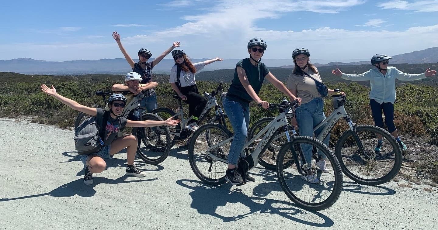 Cyclists on electric bikes along coastal hillside trail with ocean views