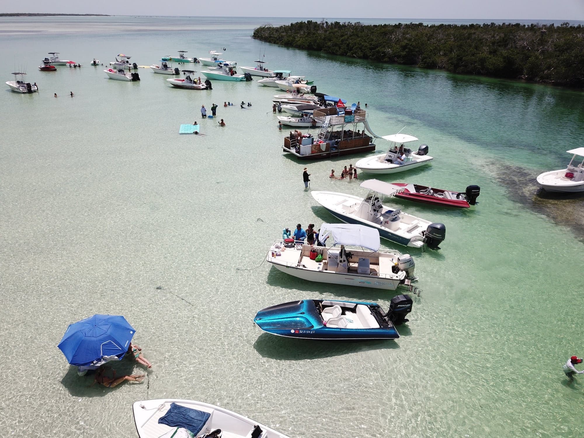 Aerial sandbar party with anchored boats in turquoise water