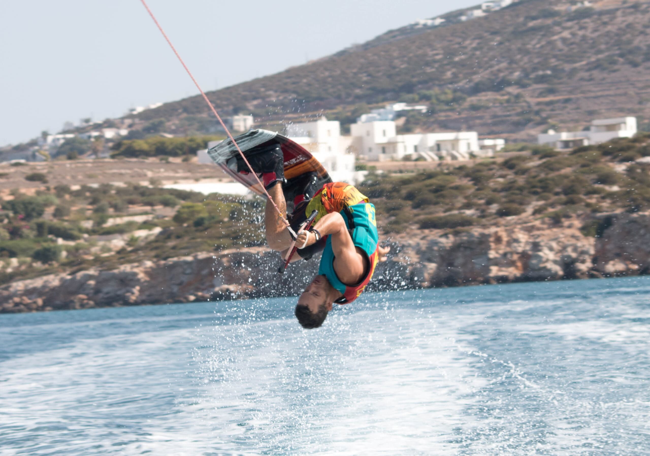 Wakeboarder launching high above wake with coastal backdrop