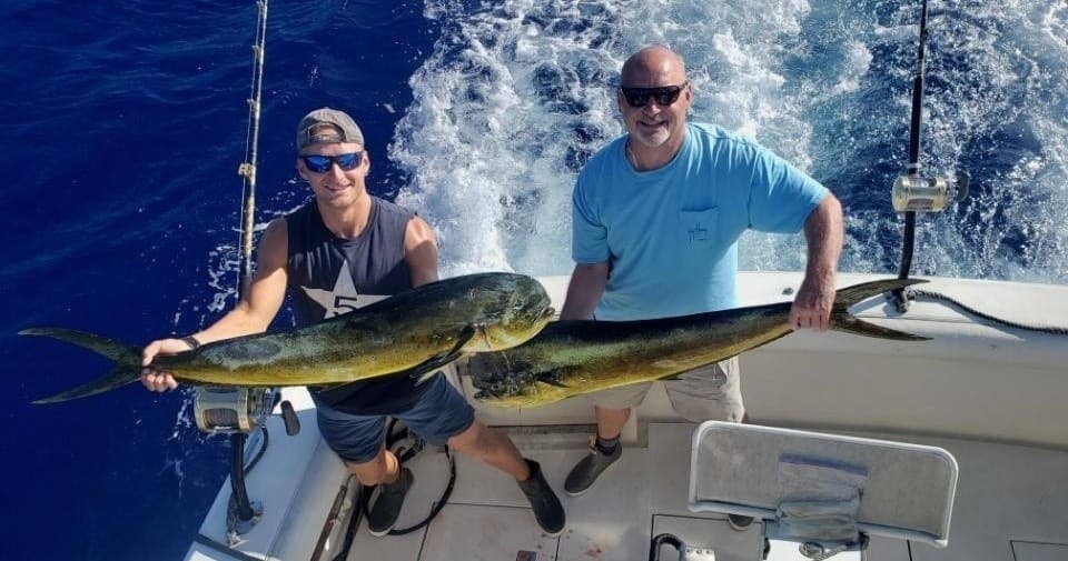 Anglers holding mahi-mahi on deck during deep sea fishing trip