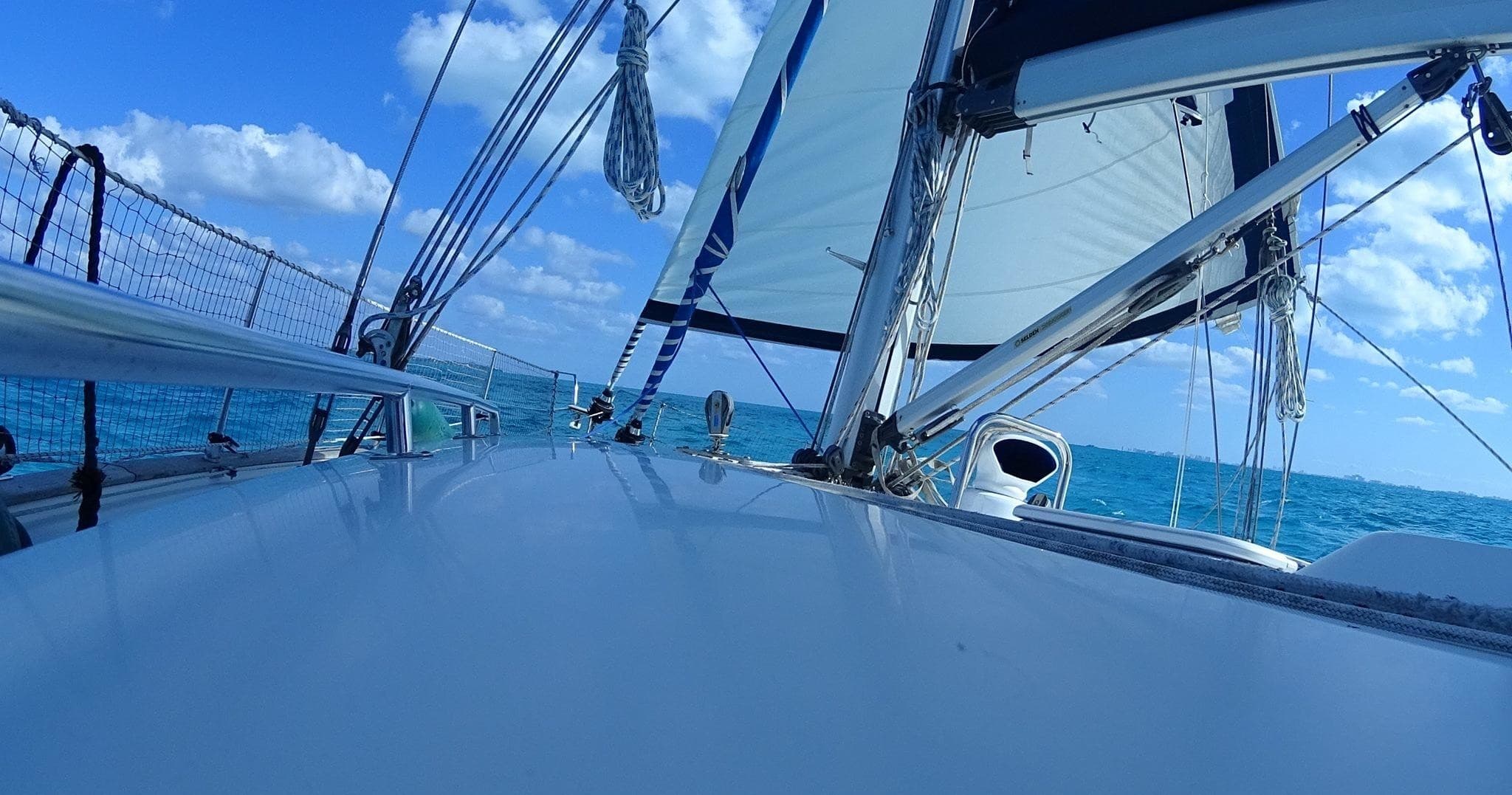 Foredeck view of sailing yacht with blue sky and tropical ocean