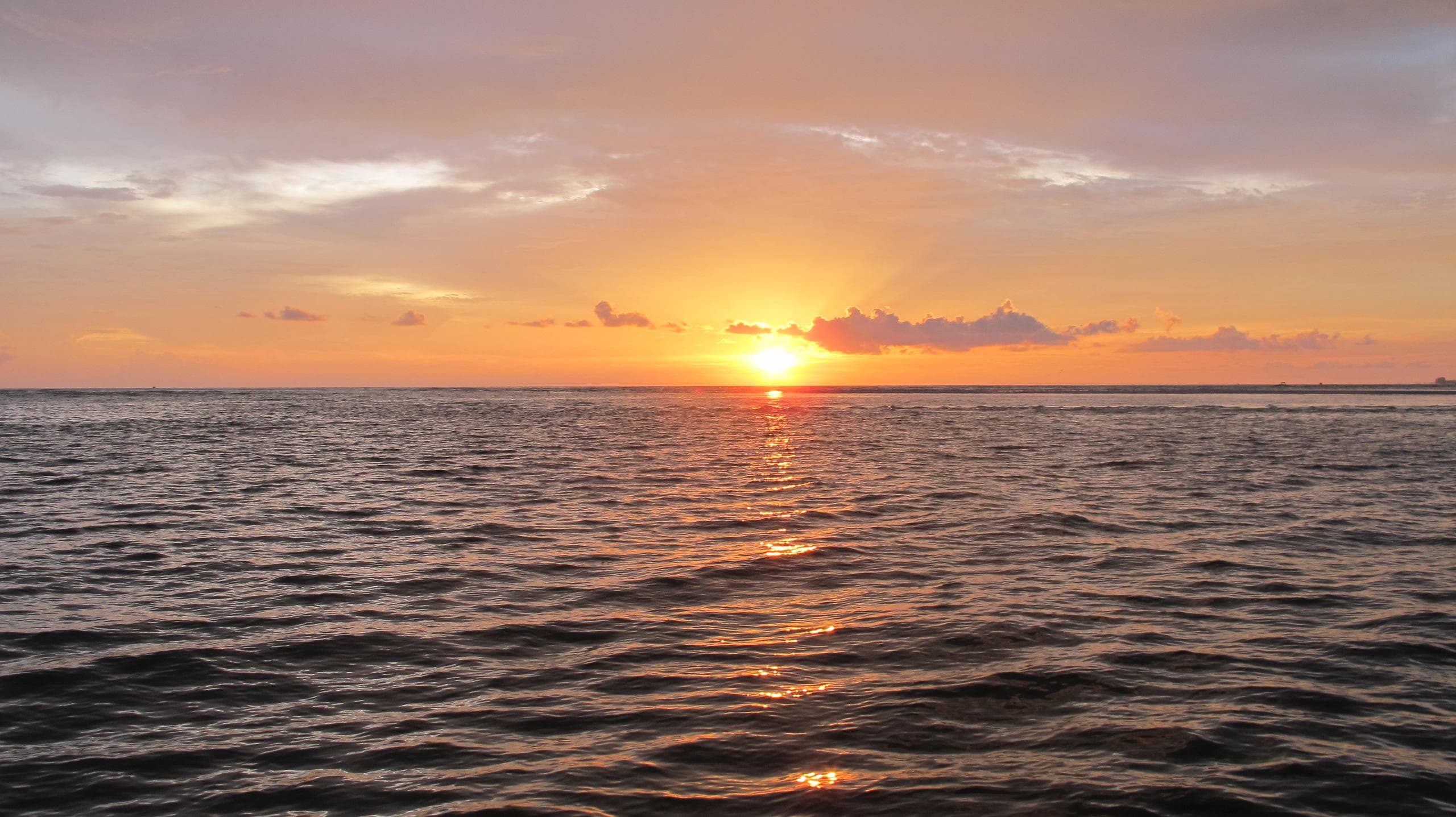 Sunset over calm ocean waters with vibrant orange horizon